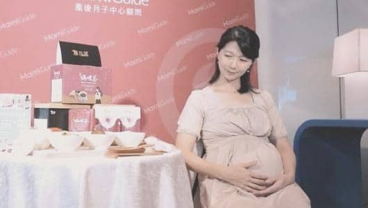 孕婦坐在 MamiGuide 品牌活動布置前